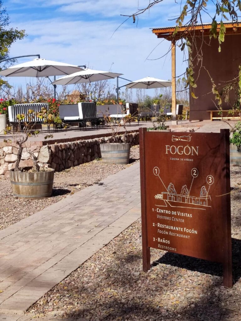 Cartel indicador de Bodega Lagarde y Restaurante Fogón con living de exterior al fondo - Mendoza Wine Transfers